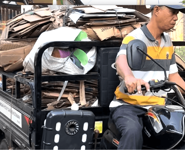 Man on motorbike carrying recyclable waste