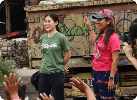Sirsak team members laughing with a community member at a waste collection site
